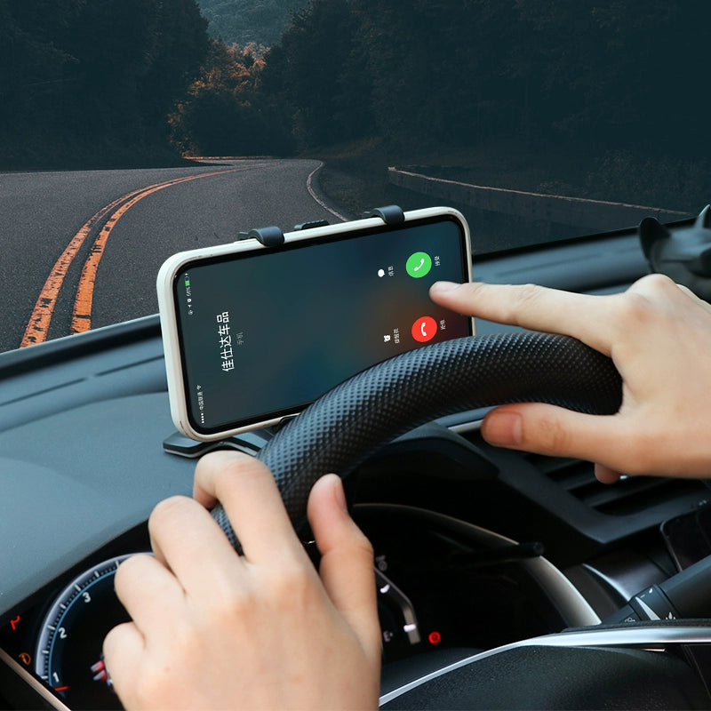 Person using a smartphone app on a car dashboard with a scenic road in the background