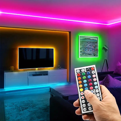 Living room with colorful LED strip lights and a hand holding a remote control.