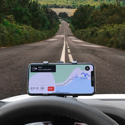 Phone with navigation app on a car dashboard over a road surrounded by trees